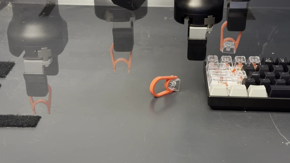 A sequence of robot poses using an orange keycap puller to remove a key from a keyboard.