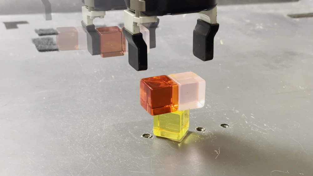 A sequence of robot poses picking up two cubes and balancing them on a yellow cube.